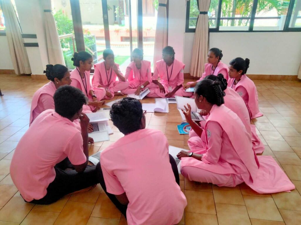 nursing students in pink uniform, sitting and discussing in a circle formation